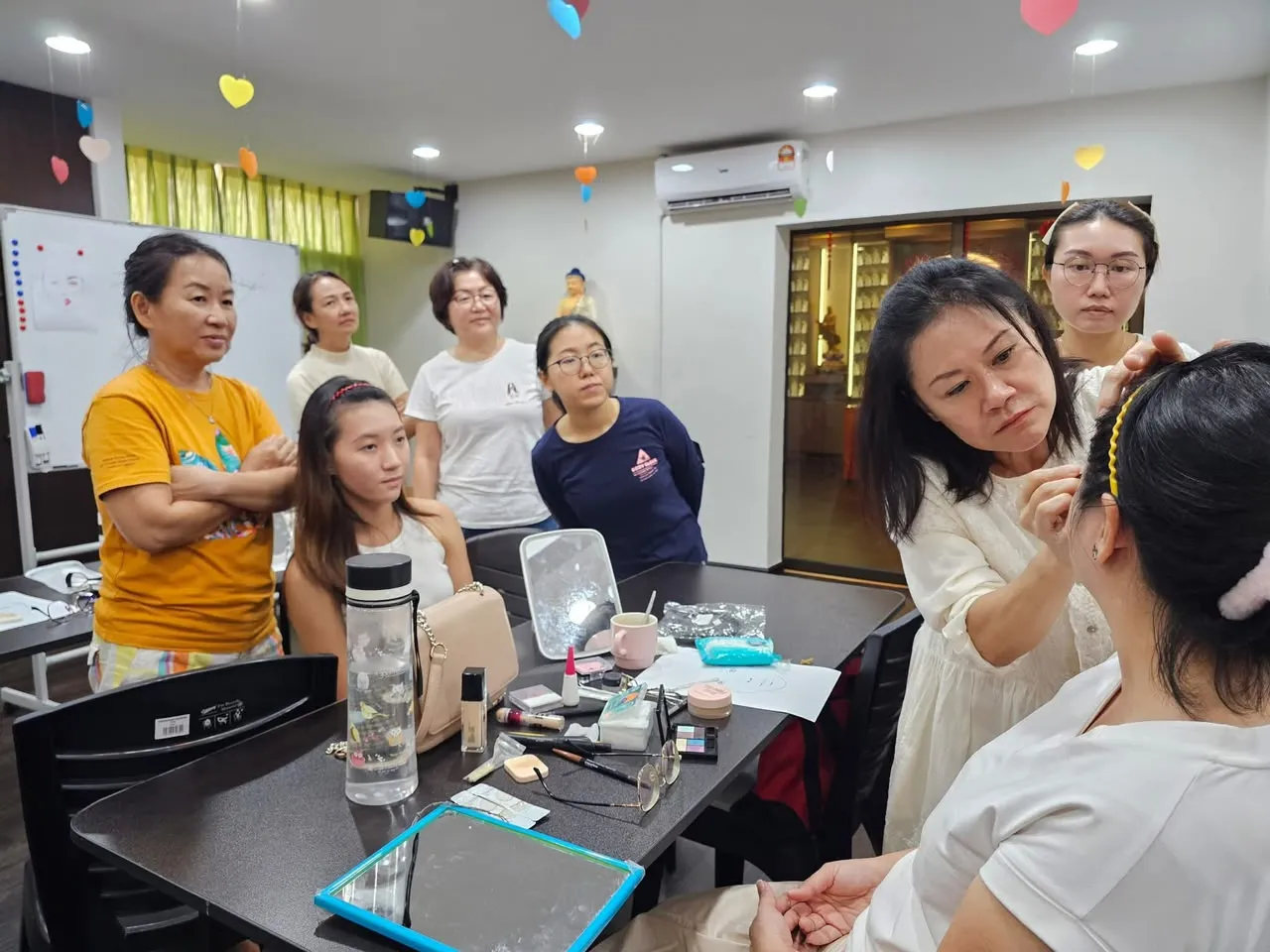 化妆工作坊导师为学员示范,其他学员在旁围观学习