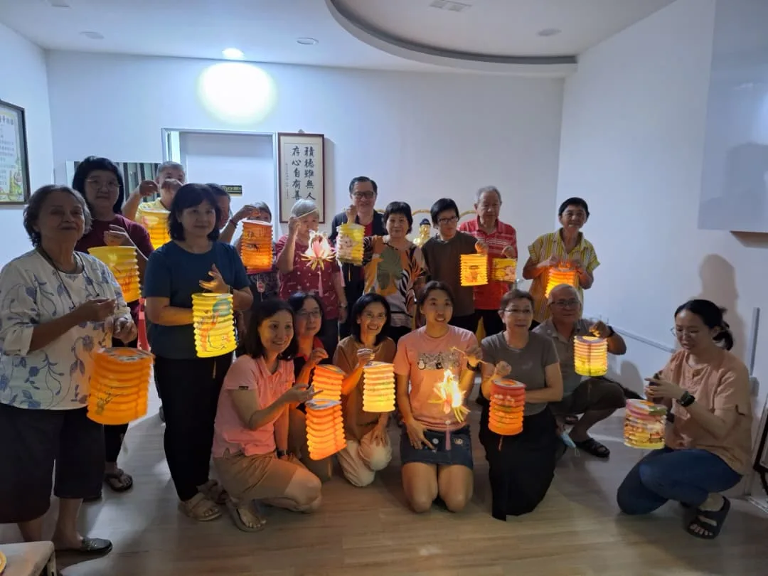长青班同修手提点亮的彩色灯笼,在课室合影庆祝中秋